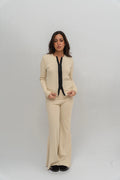 Woman wearing a beige outfit with a black top against a white background
