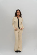 Woman wearing a beige outfit with a black top against a white background